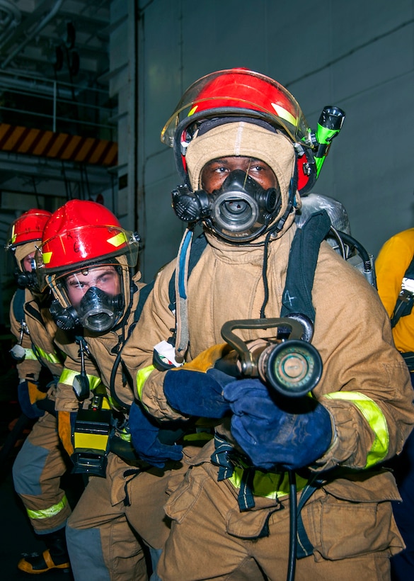 U.S. sailors participate in a fire drill in the hangar bay aboard the ...