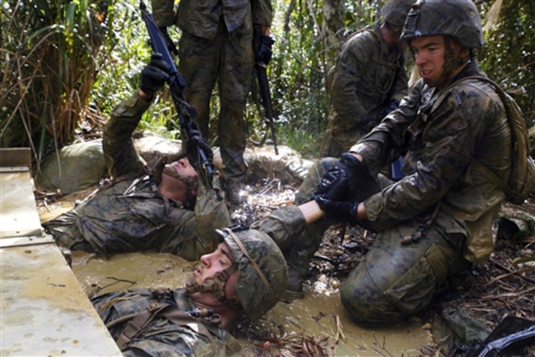 U.S. Marine Corps Lance Cpl. Jonathon E. Goff, right, helps pull Marines in his squad through an endurance course obstacle at the Jungle Warfare Training Center on Camp Gonsalves, Okinawa, Japan, Nov. 25, 2014.