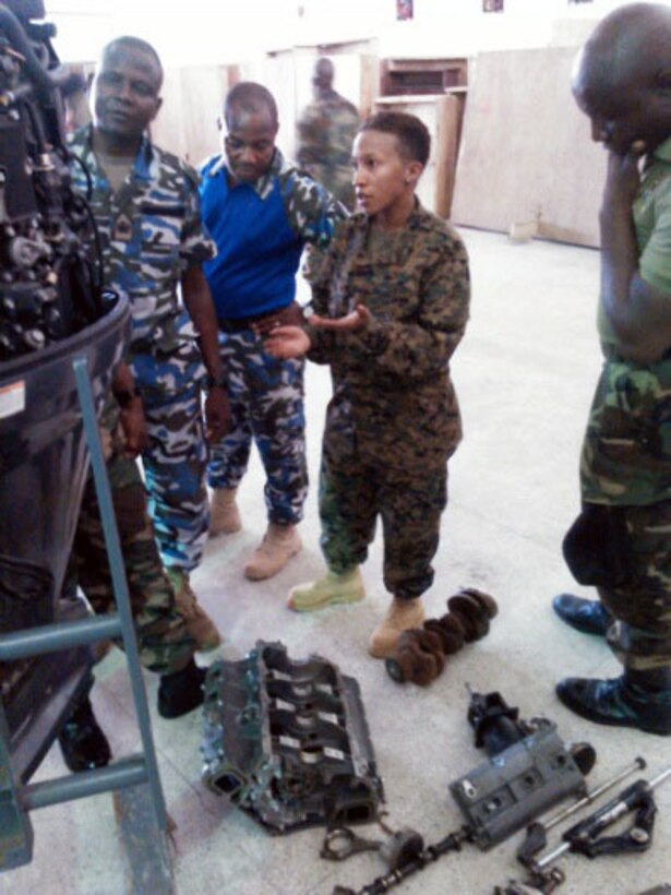 Petty Officer 2nd Class Angel Leonard shows service members with the Nigerian Navy various outboard motor parts during a training engagement in Nigeria, Dec. 2, 2014. Leonard, a Coast Guardsmen with SPMAGTF Crisis Response-Africa is working alongside service members of the Nigerian Navy for a training engagement that began in December. This training engagement will cover basic maintenance, electrical and mechanical skills, and general troubleshooting for small boat engines; the service members will share knowledge of these topics to build operational capacity between the two forces.