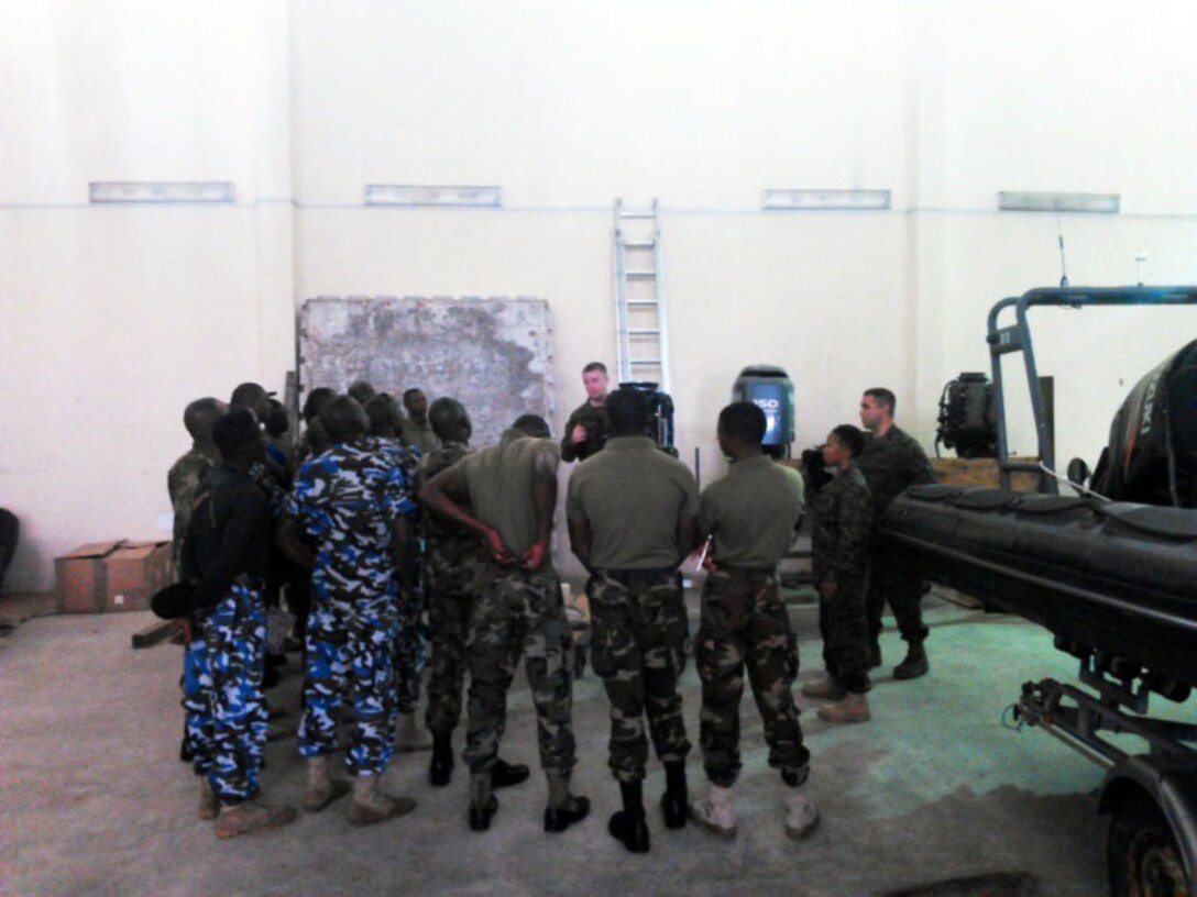 Petty Officers 2nd Class Brian Garney, Kyle Smith and Angel Leonard discuss maintenance procedures with service members from the Nigerian Navy during a training engagement in Nigeria, Dec. 2, 2014. The Coast Guardsmen joined forces with the Marines of SPMAGTF Crisis Response-Africa and are working alongside service members of the Nigerian Navy for a training engagement that began in December. This training engagement will cover basic maintenance, electrical and mechanical skills, and general troubleshooting for small boat engines; the service members will share knowledge of these topics to build operational capacity between the two forces.
