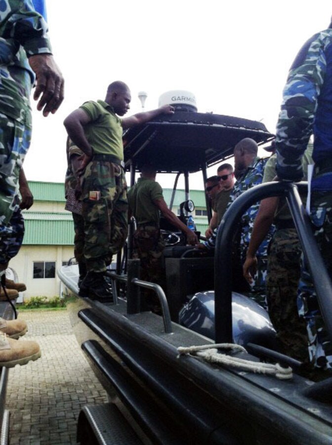 Petty Officers 2nd Class Brian Garney and Kyle Smith demonstrate boat check procedures during a training engagement with service members from the Nigerian Navy in Nigeria, Dec. 2, 2014. The Coast Guardsmen joined forces with the Marines of SPMAGTF Crisis Response-Africa and are working alongside service members of the Nigerian Navy for a training engagement that began in December. This training engagement will cover basic maintenance, electrical and mechanical skills, and general troubleshooting for small boat engines; the service members will share knowledge of these topics to build operational capacity between the two forces.