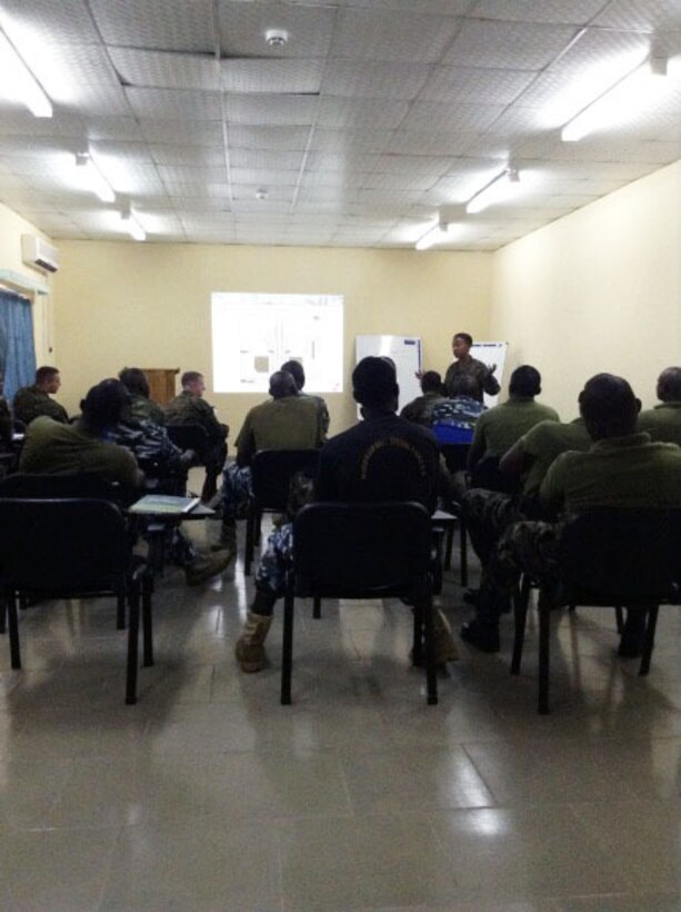 Petty Officer 2nd Class Angel Leonard discusses two-stroke and four-stroke outboard motor basics during a training engagement with service members from the Nigerian Navy in Nigeria, Dec 2, 2014. Leonard, a Coast Guardsmen with SPMAGTF-CR-AF is working alongside service members of the Nigerian Navy for a training engagement that began in December. This training engagement will cover basic maintenance, electrical and mechanical skills, and general troubleshooting for small boat engines; the service members will share knowledge of these topics to build operational capacity between the two forces.