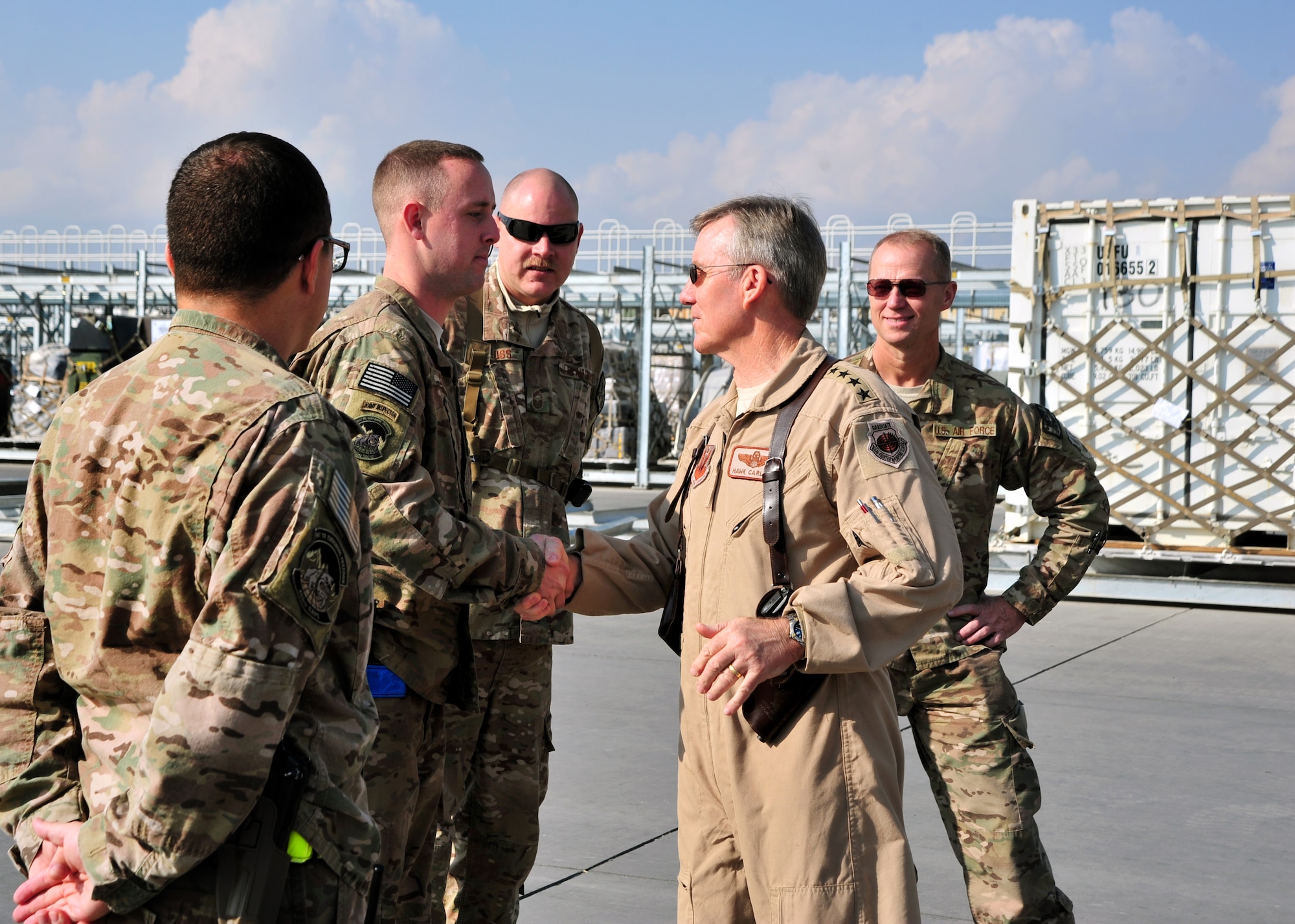 U.S. Air Force Gen. Hawk Carlisle, commander of Air Combat Command, shakes hands with U.S. Air Force Senior Airman Robert Oliver, 455th Expeditionary Aerial Port Squadron, during a visit Nov. 28, 2014 at Bagram Airfield, Afghanistan. Oliver briefed the general on the aerial port mission, retrograde operations, and upcoming mission transitions. (U.S. Air Force photo by Staff Sgt. Whitney Amstutz/released)