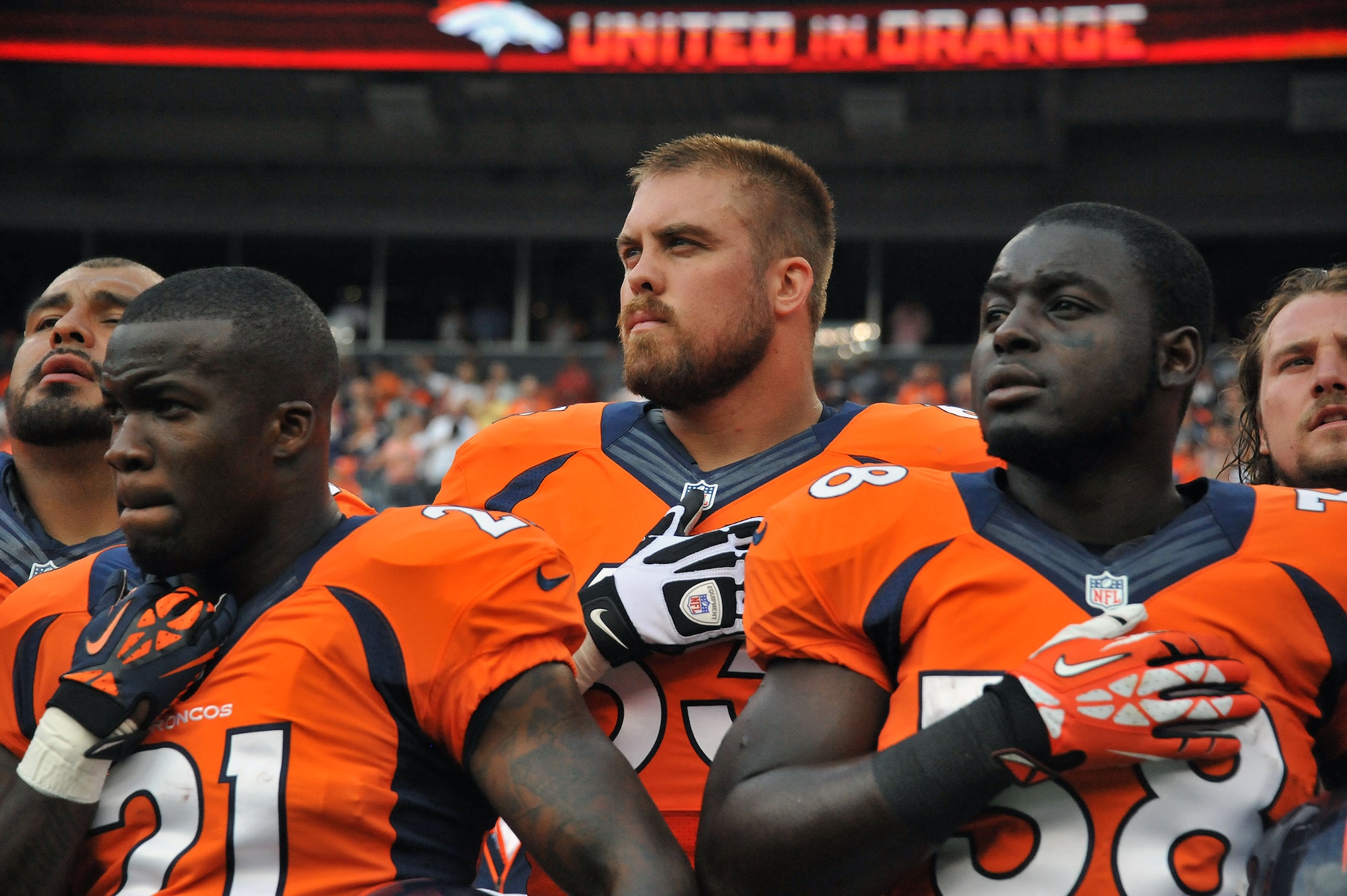 Then-1st Lt. Benjamin Garland stands with Ronnie Hillman (21) and Montee Ball (38) as he listens to the National Anthem Aug 24, 2013, at Sports Authority Field at Mile High Stadium, Denver, Colo. Garland, who originally entered the National Football League in 2010 after graduating from the U.S. Air Force Academy, was on the Bronco’s reserve/military list while fulfilling his active-duty obligations in the Air Force. In 2012 Garland joined the Colorado Air National Guard and made the Broncos practice squad as a defensive lineman and is competing this season to make the 53 man final roster. Garland is a Denver Broncos Offensive Guard and 140th Wing public affairs officer. (Air National Guard photo/Tech. Sgt. Wolfram M. Stumpf)