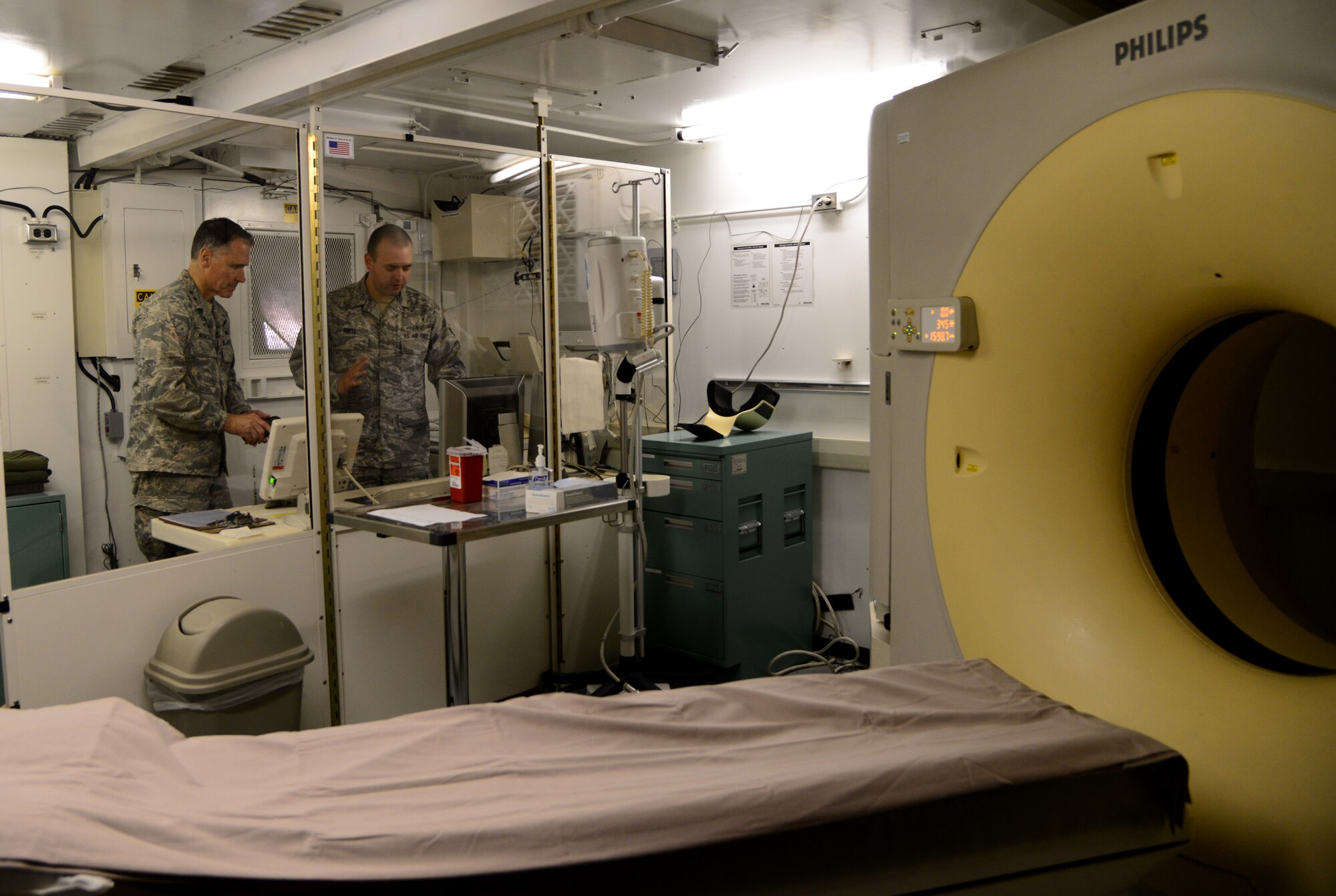 U.S. Air Force Senior Airman Brandon Roell, right, 79th Expeditionary Medical Support Squadron radiology technologist, explains computed tomography (CT) scanning protocols to U.S. Air Force Chief of Safety, Maj. Gen. Kurt Neubauer, during his visit, Dec. 2, 2014, to Al Udeid Air Base, Qatar. Roell recently received an award of distinction for his outstanding contribution to ground safety. While reading a civilian medical journal, Roell discovered that new CT parameters have the potential to reduce a patient's radiation dose while maintaining the quality of the diagnostic images. He used this knowledge, combined with his previous experience, to engineer new CT scanning protocols, which ultimately results in improved safety for patients. (U.S. Air Force photo by Senior Airman Kia Atkins)