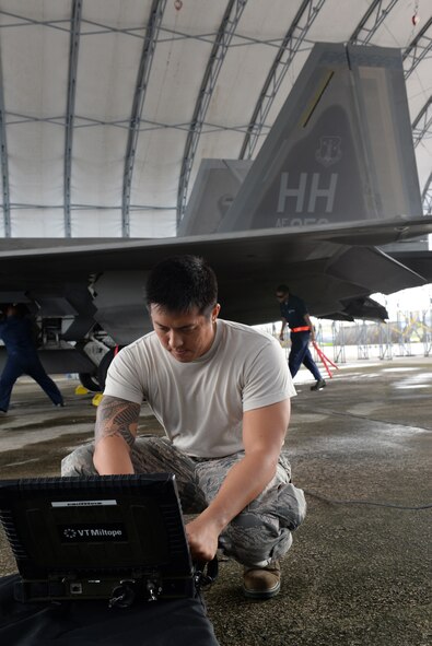 Tech. Sgt. Howard Uyeda, 154th Aircraft Maintenance Squadron avionics technician from Joint Base Pearl Harbor-Hickam, Hawaii, turns on a computer to connect to an F-22 Raptor Nov. 24, 2014, at Andersen Air Force Base, Guam. A C-17 Globemaster III along with several F-22s operated from Andersen to practice flexibility in aircraft movement at a non-traditional base with additional pilots, maintenance support and accompanying fuel and munitions. (U.S. Air Force photo by Airman 1st Class Amanda Morris/Released)