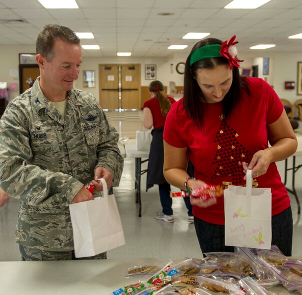 Col. Randy Huiss, 15th Wing commander, left, and Kristianne Swanson, Hickam Enlisted Spouses Club president, stuff cookie bags for the Cookie Caper in the Cookie Command Central at the Makai Recreation Center on Joint Base Pearl Harbor-Hickam, Hawaii, Dec. 3, 2014. The Cookie Caper program solicits donations for freshly baked cookies from base and community members. Caper "elves" then collect and sort the cookies in holiday-themed bags, which are distributed to base Airmen. (U.S. Air Force photo by Tech. Sgt. Terri Paden/RELEASED)