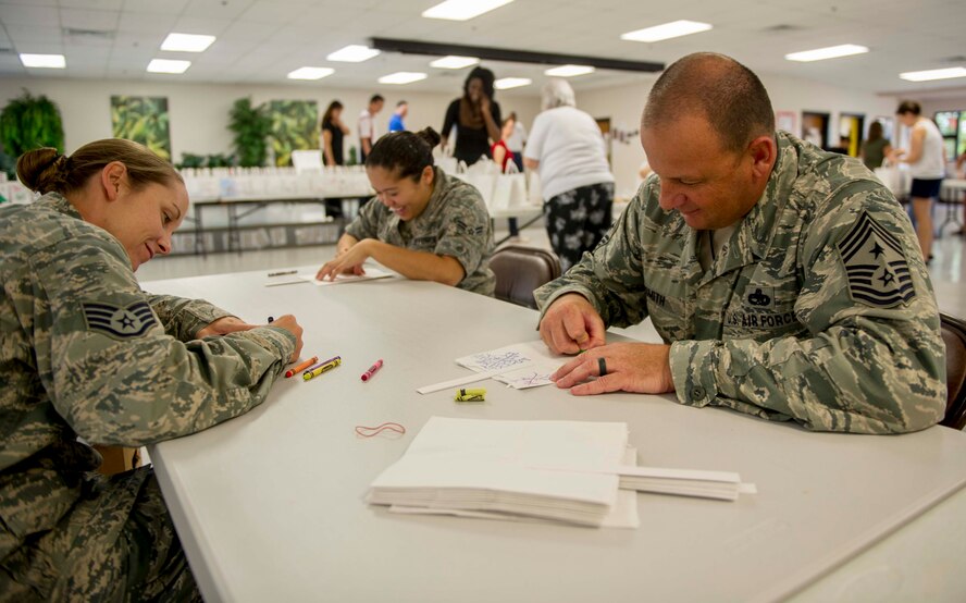 Staff Sgt. Melissa Paul, Executive Assistant to the 15th Wing command chief, left, and Chief Master Sgt. James Smith, 15th WG command chief, right, decorate bags for the Cookie Caper in the Cookie Command Central at the Makai Recreation Center on Joint Base Pearl Harbor-Hickam, Hawaii, Dec. 3, 2014. The Cookie Caper program solicits donations for freshly baked cookies from base and community members. Caper "elves" then collect and sort the cookies in holiday-themed bags, which are distributed to base Airmen. (U.S. Air Force photo by Tech. Sgt. Terri Paden/RELEASED)