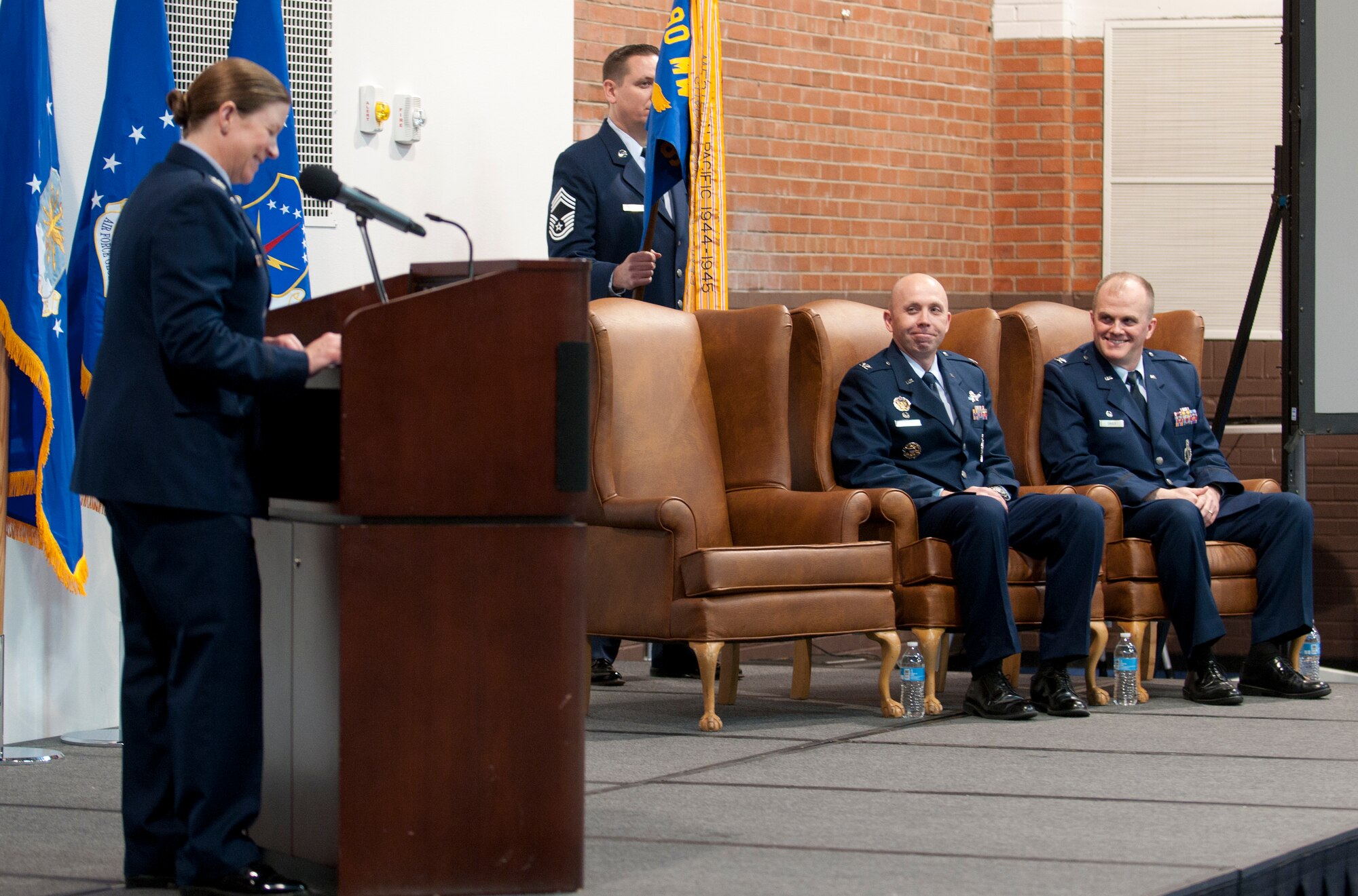Col. Tracey Hayes, 90th Missile Wing commander, addresses Col. Todd Sauls, 90th Operations Group commander, and Col. Ron Allen, 90th MW vice commander, during her comments at the 90th Operations Group change-of-command ceremony in the Fall Hall community center on F.E. Warren Air Force Base, Wyo., Dec. 3, 2014. Sauls assumed command of the group from Allen who has been assigned as the 90th MW vice commander. (U.S. Air Force photo/ Airman 1st Class Malcolm Mayfield)