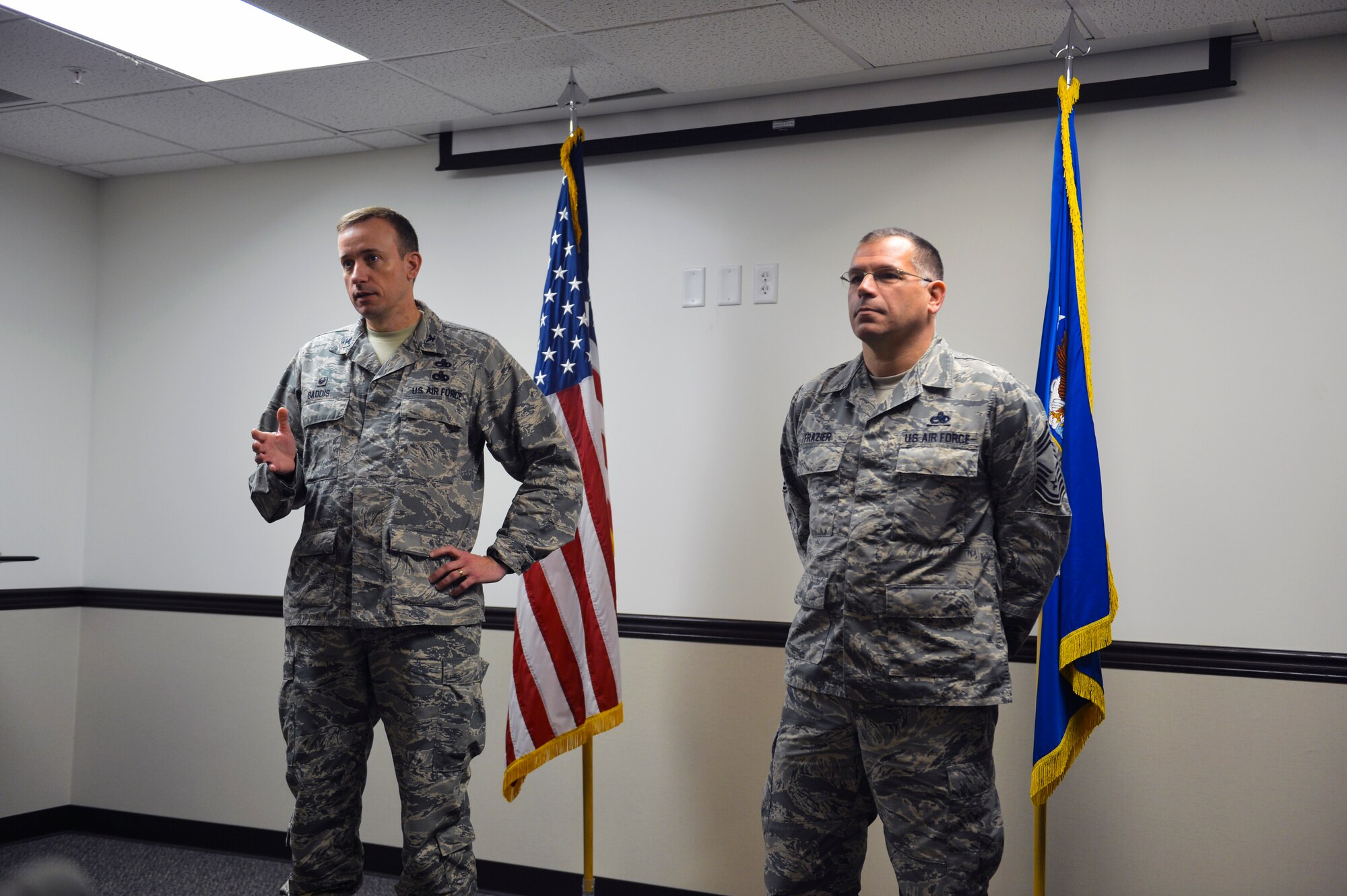 Col. Craig Gaddis (left), 62nd Maintenance Group commander, talks about  the accomplishments of Chief Master Sgt. John Frazier (right), 62nd MXG superintendent, for which he was awarded the Bronze Star medal during an award ceremony Dec. 3, 2014, at Joint Base Lewis-McChord, Wash. Frazier was deployed to Bagram Airfield in Afghanistan from April through October of 2014 as the group level maintenance chief and melded a group of more than 1,300 total force Airmen from across six rotations into a cohesive aircraft and munitions maintenance team. (U.S. Air Force photo/Staff Sgt. Russ Jackson)