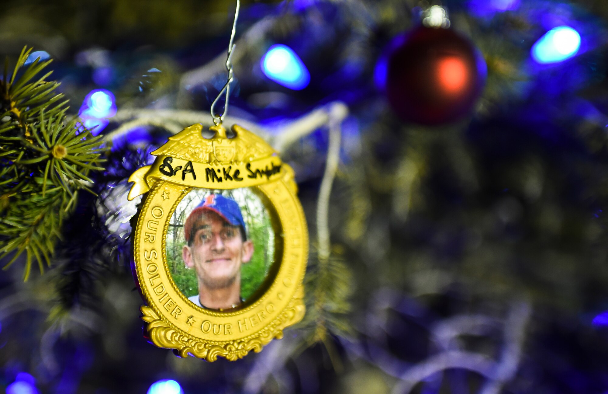 Family members of the late Senior Airman Kristopher Mansfield hung an ornament with a picture of Senior Airman Michael Snyder on Mandfield's memorial tree during a ceremony Dec. 2, 2014, on Buckley Air Force Base, Colo. The tree-lighting ceremony honored Mansfield and Snyder, both members of the 460th Space Communications Squadron who were killed by drunk drivers. (U.S. Air Force photo by Senior Airman Riley Johnson/Released)