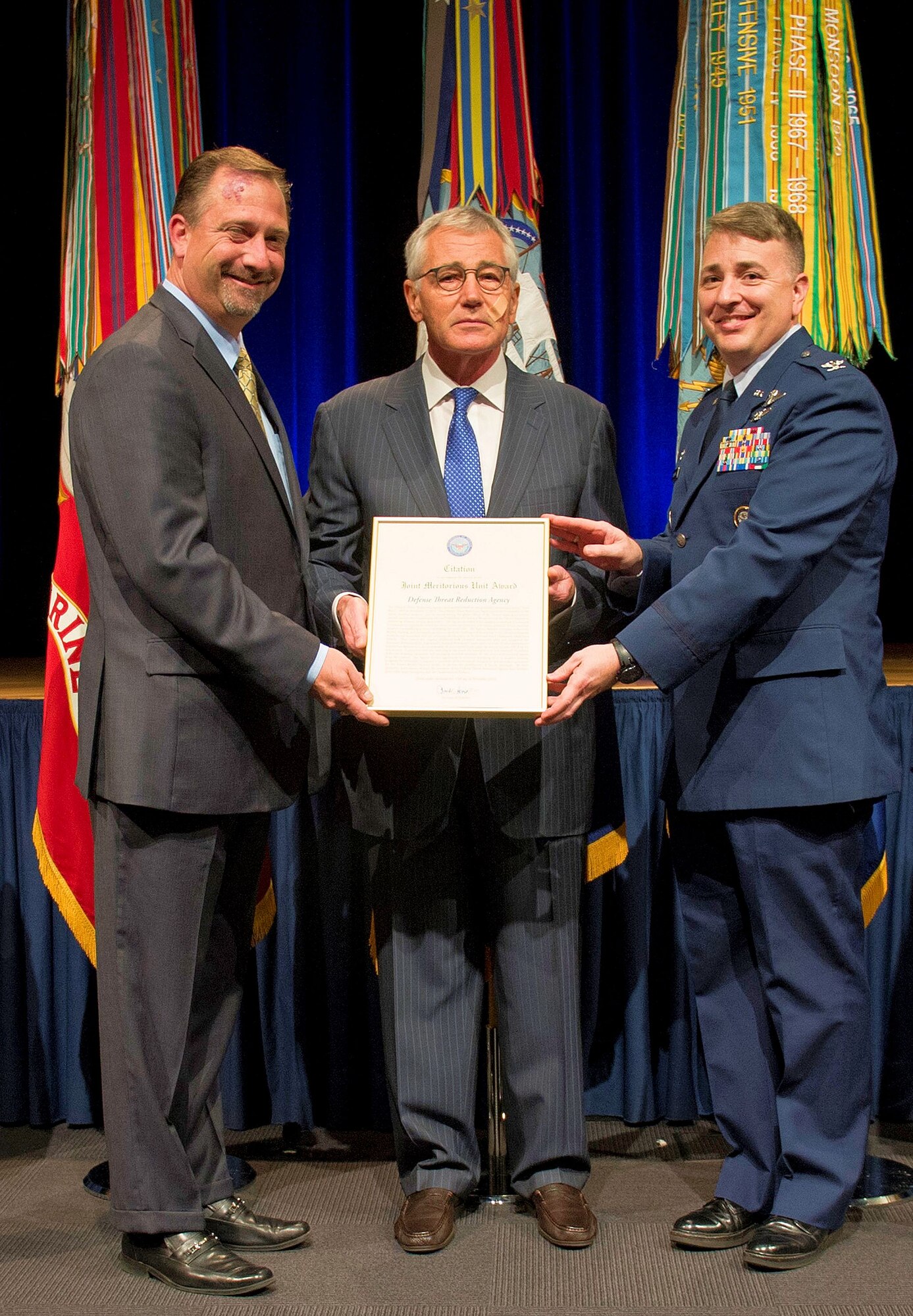 Col. John Cinnamon (right), the 71st Operations Group commander, and Ken Myers (left), the Defense Threat Reduction Agency director, accept a Joint Meritorious Unit Award from Secretary of Defense Chuck Hagel, during a ceremony at the Pentagon Nov. 12. Cinnamon was the chief of plans for DTRA from June 2012 to June 2014 before he joined Team Vance.  (U.S. Air Force photo/MSgt. Adrian Cadiz)
