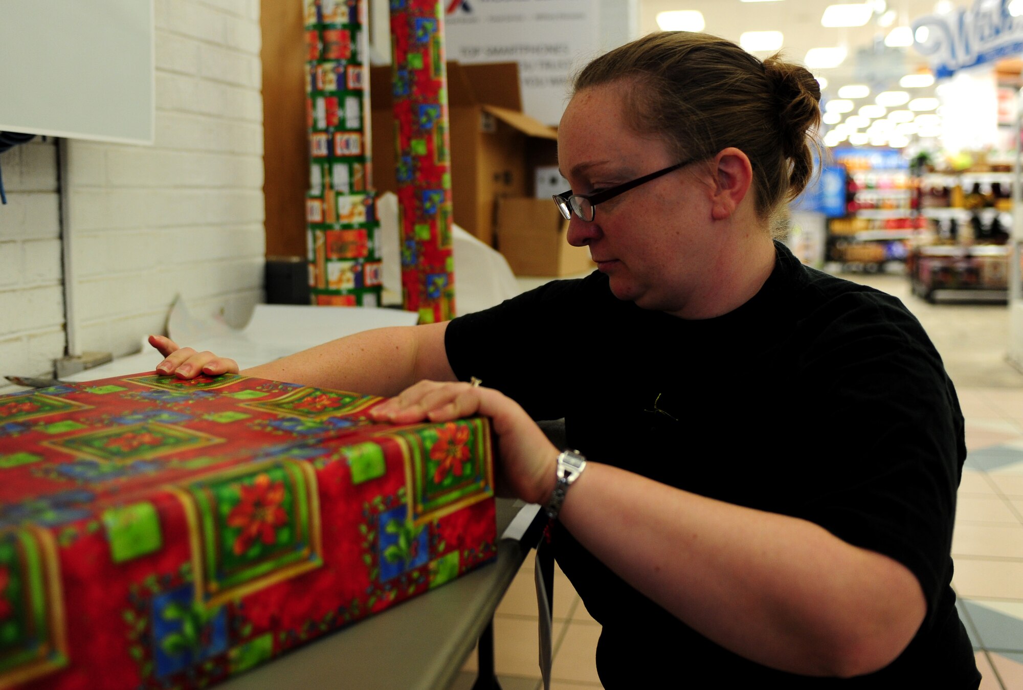 U.S. Air Force Capt. Heather Ross, 27th Intelligence Squadron flight commander, wraps a gift at Langley Air Force Base, Va., Dec. 2, 2014. All supplies were provided by the Base Exchange to assist volunteers in collecting donations for their individual units’ morale events. (U.S. Air Force photo by Airman 1st Class Areca T. Wilson/ Released) 
