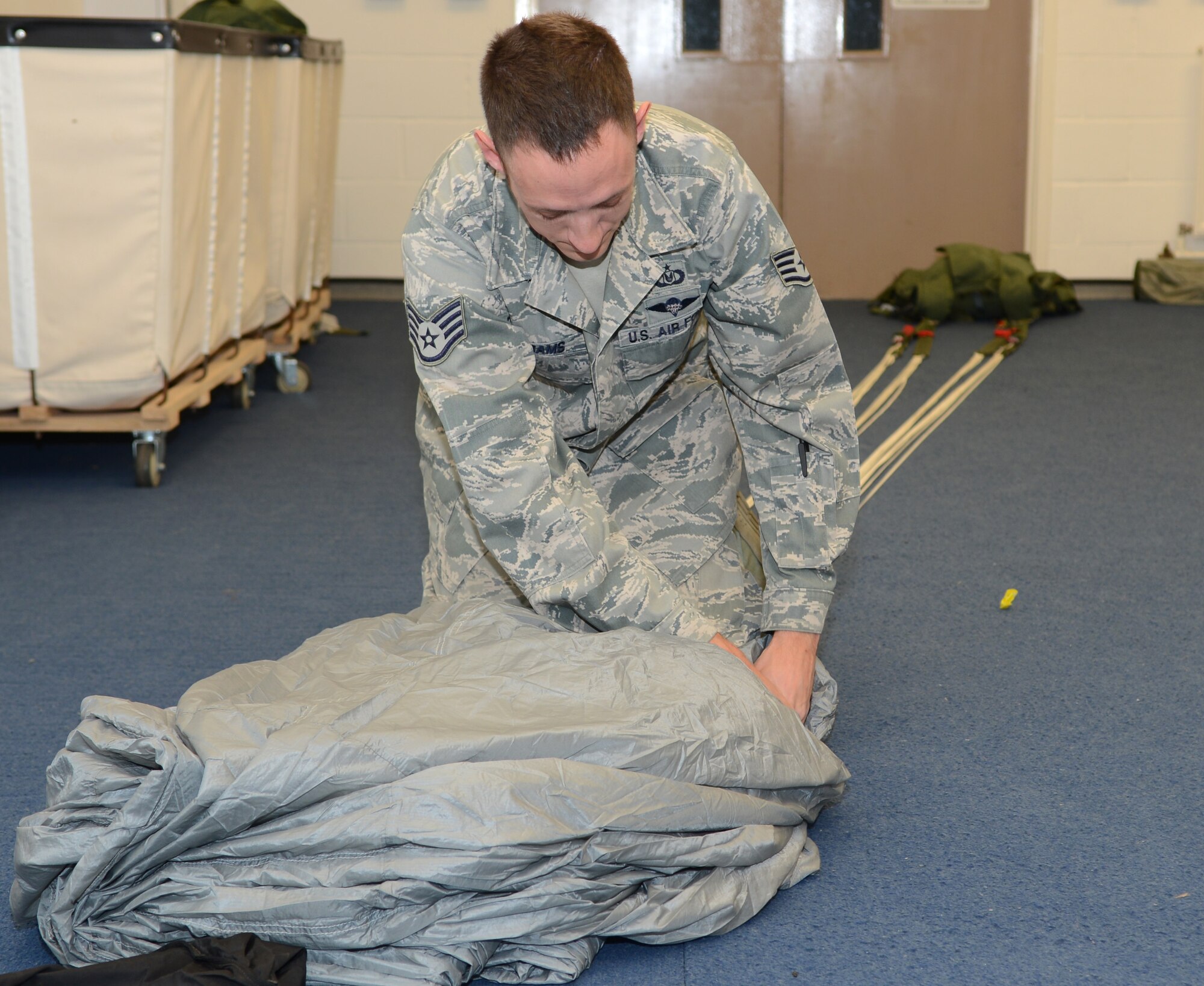 U.S. Air Force Staff Sgt. Patrick Adams, 321st Special Tactics Squadron aircrew flight equipment craftsman from Fort Smith, Ark., folds a static-line parachute Nov. 5, 2014, at building 814 on RAF Mildenhall, England. In order to be qualified on packing a static-line parachute, an AFE Airman must be able to perform the task in 30 minutes or less. (U.S. Air Force photo by Airman 1st Class Dillon Johnston/Released)