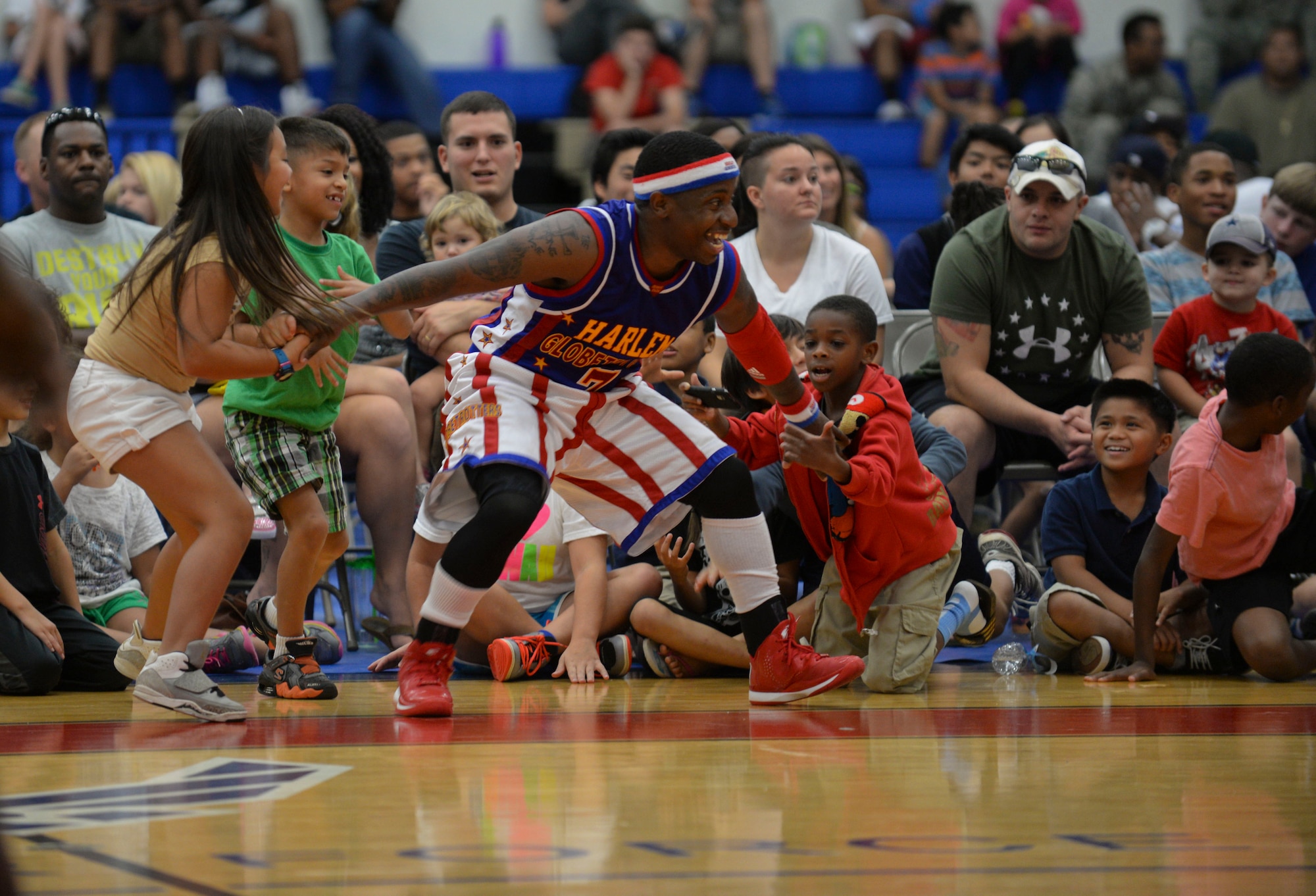 Too-Tall, from The Harlem Globetrotters, interact with children from Team Andersen during an exhibition basketball game against the Washington Generals, Dec. 1, 2014, at Andersen Air Force Base, Guam. The Globetrotters captivated Team Andersen with their athleticism, theater and comedy as well as its audience participation, choreography, tricks and their overall basketball skill. (U.S. Air Force photo by Staff Sgt. Robert Hicks/Released)  