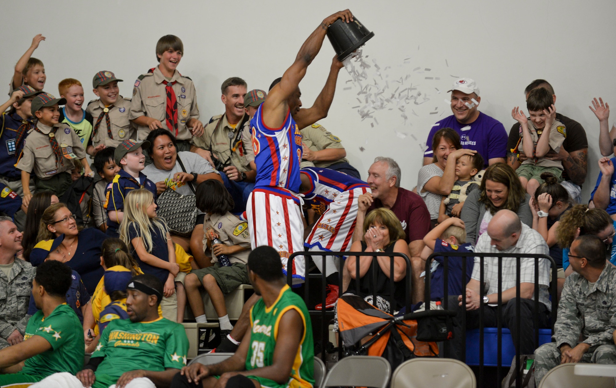 Hi-Lite, from The Harlem Globetrotters, dumps a bucket of paper onto the fans, Dec. 1, 2014, at Andersen Air Force Base, Guam. The Globetrotters captivated Team Andersen with their athleticism, theater and comedy as well as its audience participation, choreography, tricks and their overall basketball skill. (U.S. Air Force photo by Staff Sgt. Robert Hicks/Released)   