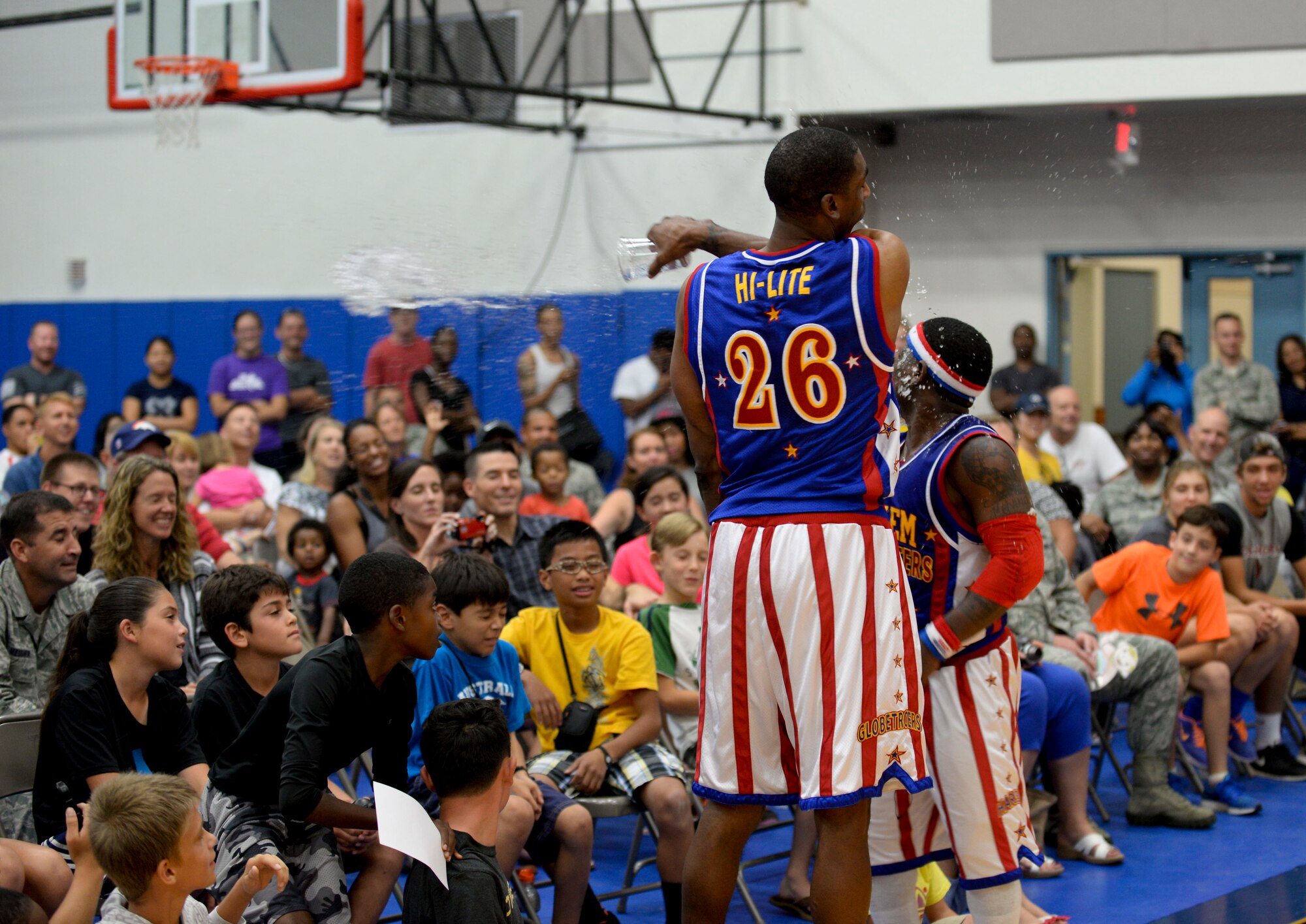 Hi-Lite splashes a cup of water into Too-Tall’s face, both members of the Harlem Globetrotters, during an exhibition basketball game against the Washington Generals, Dec. 1, 2014, at Andersen Air Force Base, Guam. The Globetrotters captivated Team Andersen with their athleticism, theater and comedy as well as its audience participation, choreography, tricks and their overall basketball skill. (U.S. Air Force photo by Staff Sgt. Robert Hicks/Released)  
