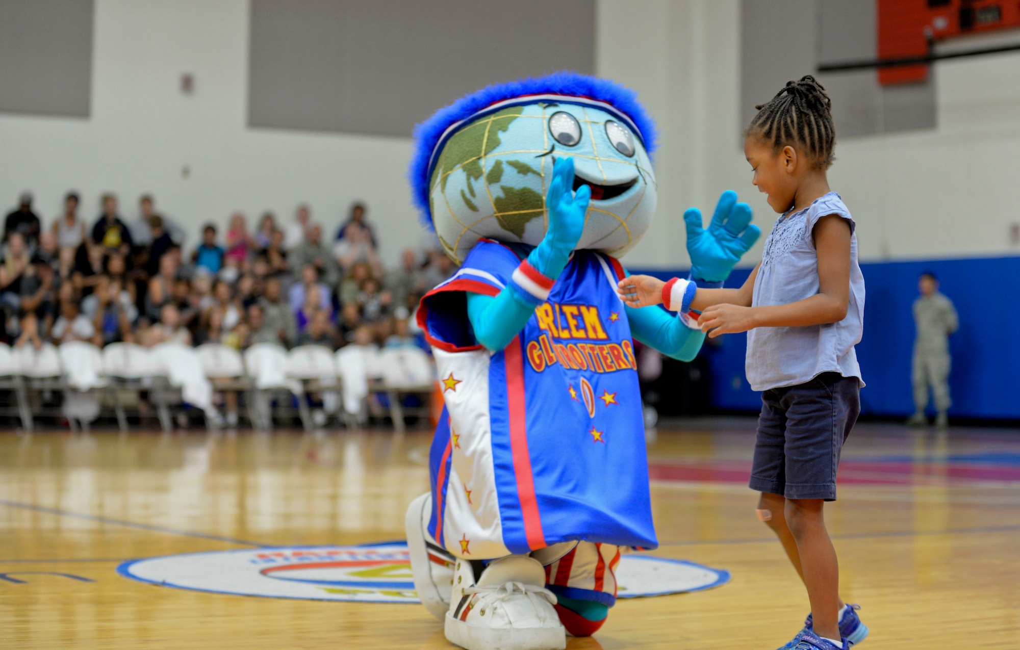 Globie, the Harlem Globetrotter mascot, gives a wristband to a Team Andersen member after winning a game of musical chairs, Dec. 1, 2014, at Andersen Air Force Base, Guam. The Globetrotters captivated Team Andersen with their athleticism, theater and comedy as well as its audience participation, choreography, tricks and their overall basketball skill. (U.S. Air Force photo by Staff Sgt. Robert Hicks/Released)  