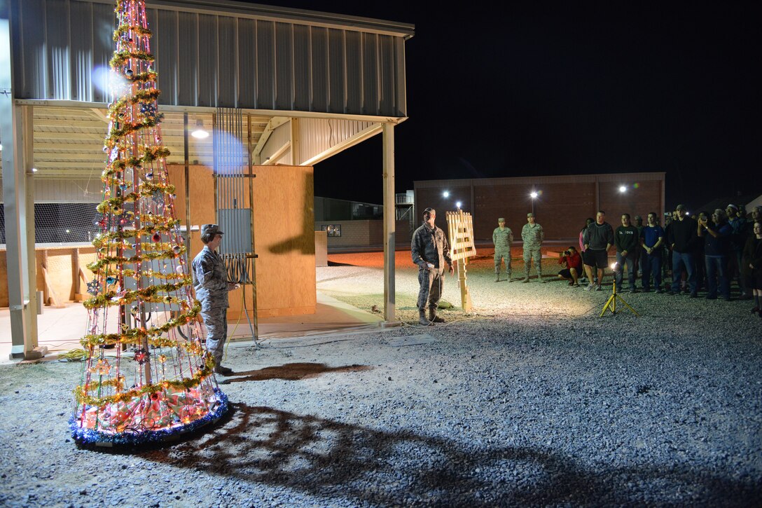 SOUTHWEST ASIA - Col. Jason Hanover (right), 386th Air Expeditionary Wing commander, and Chief Master Sgt. Jan Menard, 386th AEW acting command chief, turn on the holiday lights here Dec. 3, 2014. Hanover lit the menorah while Menard lit the tree, as a way to officially usher in the holiday season. (U.S. Air Force photo by Tech. Sgt. Jared Marquis/released)