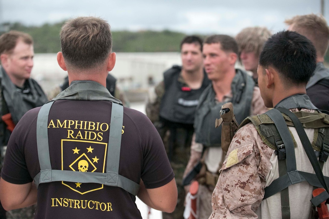 Sgt. Jon C. Walters, left, from Matoaca, Virginia, briefs the Marines over the procedures of engaging urban terrain from the water Oct. 30 at White Beach Naval Facility during the scout swimmers course. The course is 3 weeks long, and progresses the students by taking the skills they learn in the pool and the classroom to the ocean. Walters is the senior amphibious raid instructor with Expeditionary Operations Training Group, III Marine Expeditionary Force Headquarters Group, III MEF. 