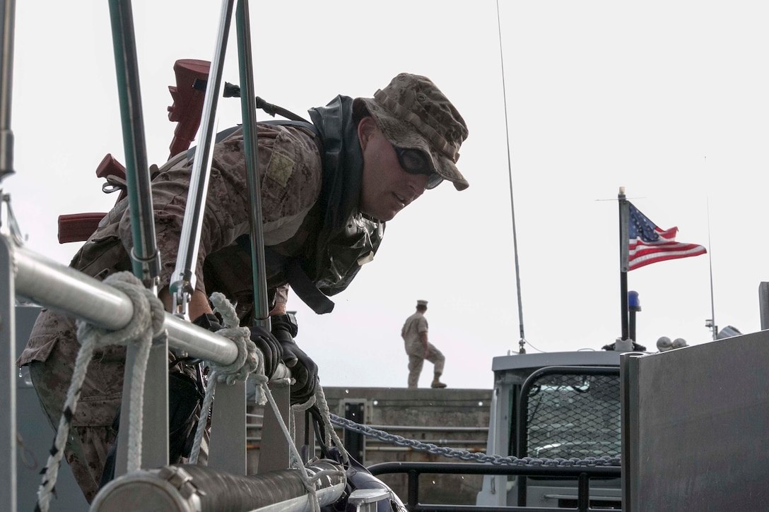 Maj. Breck Perry, from Fredericksburg, Virginia, climbs onto a boat from the water Oct. 30 at White Beach Naval Facility during the scout swimmers course. The students were tasked to stealthily approach urban terrain from the water to exercise insertion techniques. Perry is a student of the course with Expeditionary Operations Training Group, III Marine Expeditionary Force Headquarters Group, III MEF. 