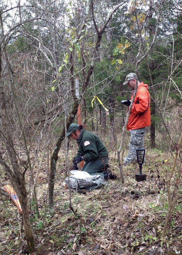 Stephanie Ison, natural resources specialist ranger, and Greg Guay, maintenance mechanic, of Brookville Lake use a GPS unit to mark and uncover a Corps property monument that was buried beneath five inches of dirt.
