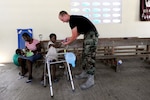 An Airman with the 118th Civil Engineering Squadron, gives candy to a child at the New Life Children's Home in Port au Prince, Haiti, Friday, March 12, 2010. Members of the squadron have been working at the home, a local orphanage that has also taken in many children injured by the January earthquake, building cabinets, storage areas and a medical clinic.