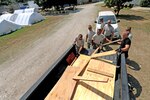 Members of the 118th Civil Engineering Squadron remove lumber from the back of a truck as they begin work on various construction projects at the New Life Children's Home in Port au Prince, Haiti, Friday, March 12, 2010. Members of the squadron have been working at the home, a local orphanage that has also taken in many children injured by the January earthquake, building cabinets, storage areas and a medical clinic.