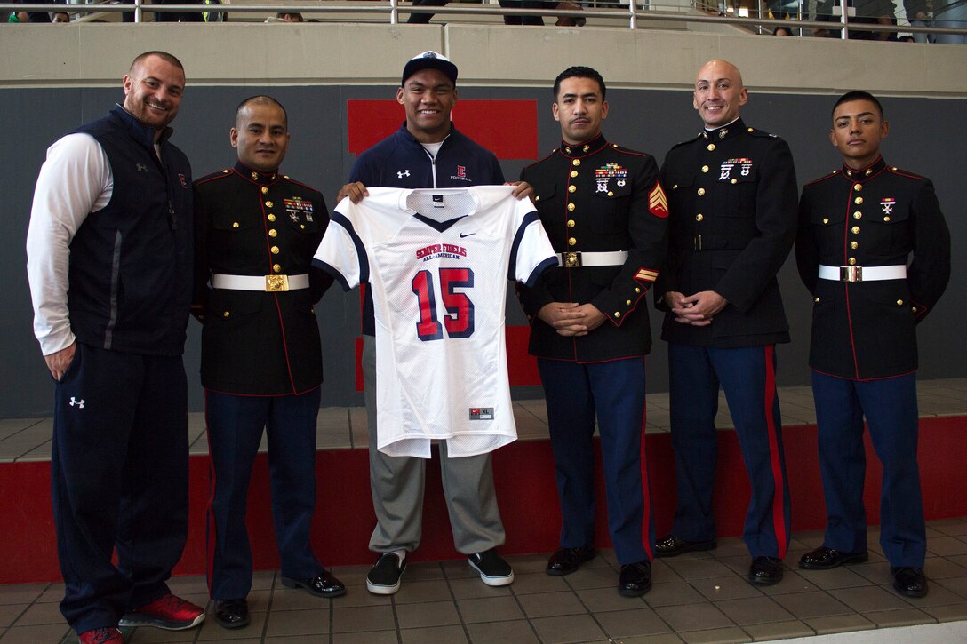 Marines with Recruiting Station Salt Lake City present Christian Folau with a jersey for the Marine Corps’ Semper Fi All-American Bowl Nov. 14 at East High School, Salt Lake City. Folau was selected for his talents on the field and in the classroom.