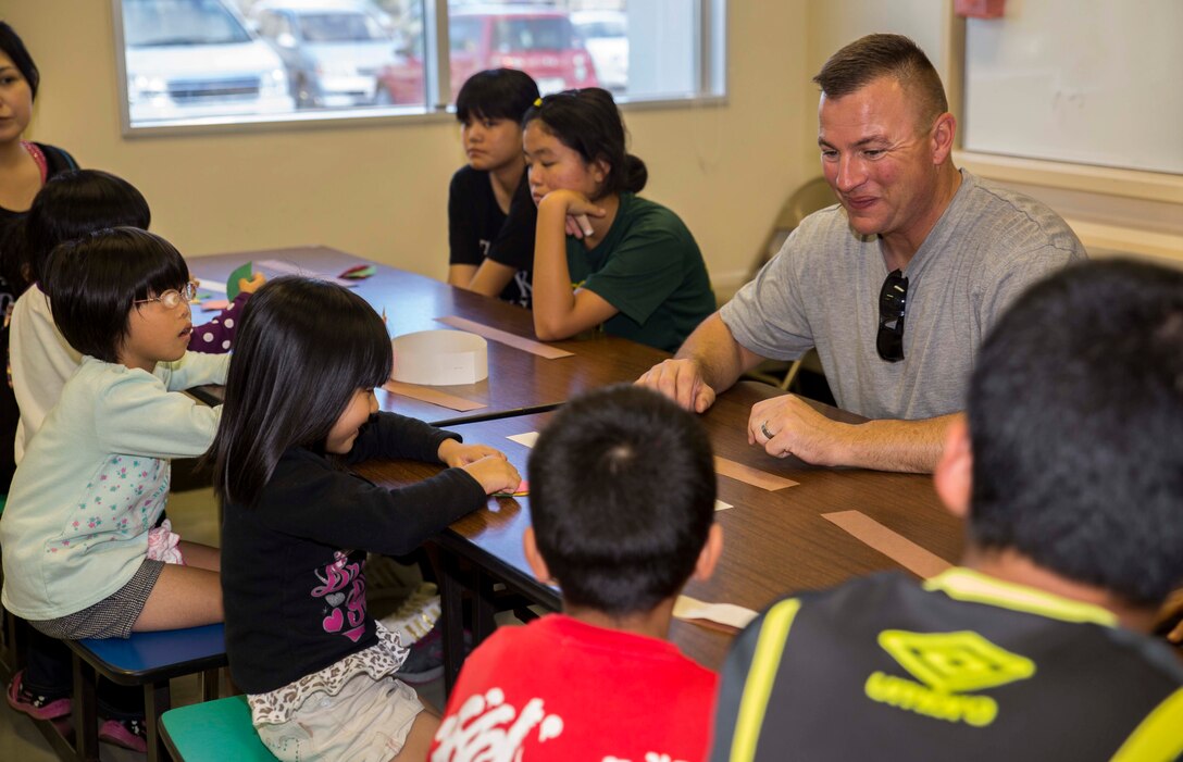 Gunnery Sgt. Shane R. Bertrand, from Ontario, Oregon, helps children put together paper pilgrim and American Indian hats Nov. 23 during the second annual Thanksgiving celebration with Tai Chu En Children’s Home at the Camp Kinser Chapel. This was the second annual Thanksgiving event with the children’s home and the Marines and sailors with Combat Logistics Regiment 35. Following the crafts, the children and volunteers sat down for a Thanksgiving feast including turkey, corn and pumpkin pie. Bertrand is the logistics chief for CLR 35, 3rd Marine Logistics Group, III Marine Expeditionary. 