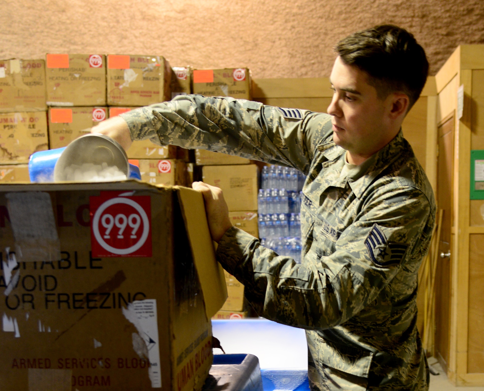 U.S. Air Force Staff Sgt. Chayce Trotter, 379th Expeditionary Medical noncommissioned officer in charge of the Blood Transshipment Center, packs dry ice, Dec. 4, 2014, at Al Udeid Air Base, Qatar. When blood products are shipped throughout U.S. Central Command’s Area of Responsibility, dry ice is used to keep the products at the correct temperature. (U.S. Air Force photo by Senior Airman Kia Atkins)