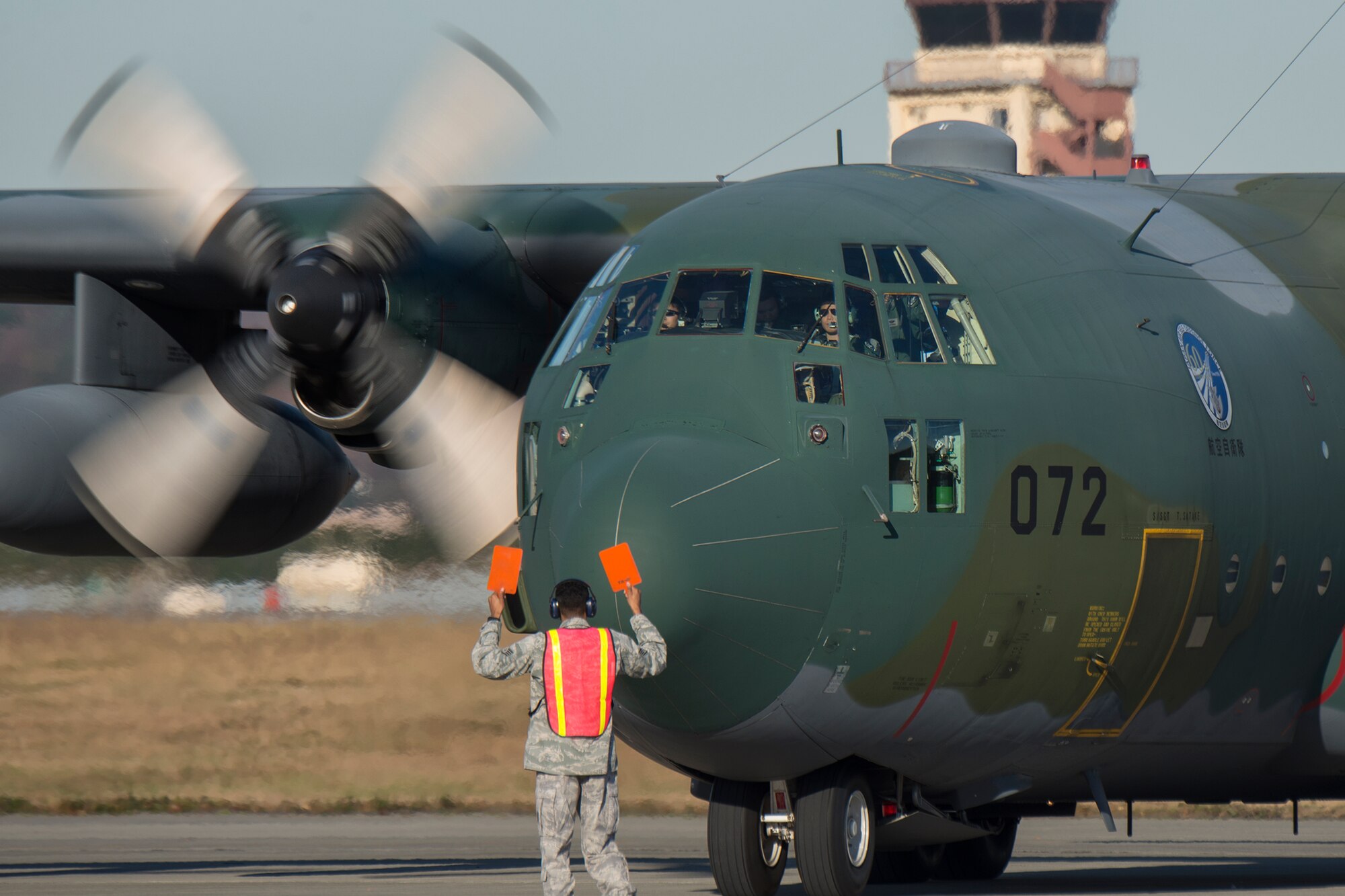An airman from the 374th Maintenance Squadron marshals a Japan Air Self-Defense Force’s C-130 Hercules at Yokota Air Base, Japan, Dec. 3, 2014. This is the 2nd year the JASDF members from 401st Squadron, Komaki Air Base delivered Operation Christmas Drop donations. (U.S. Air Force photo by Osakabe Yasuo/Released)  