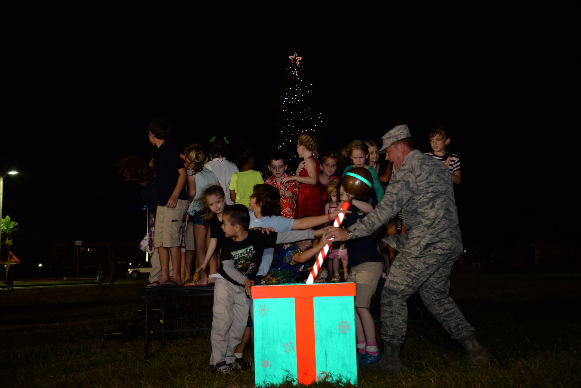 Col. Tyrell Chamberlain, 36th Wing vice commander, and children from Team Andersen flip on the lights during the base tree lighting ceremony Dec. 2, 2014, at Andersen Air Force Base, Guam. Andersen held the annual ceremony to bring families together during the holiday season. (U.S. Air Force photo by Airman 1st Class Amanda Morris/Released.)