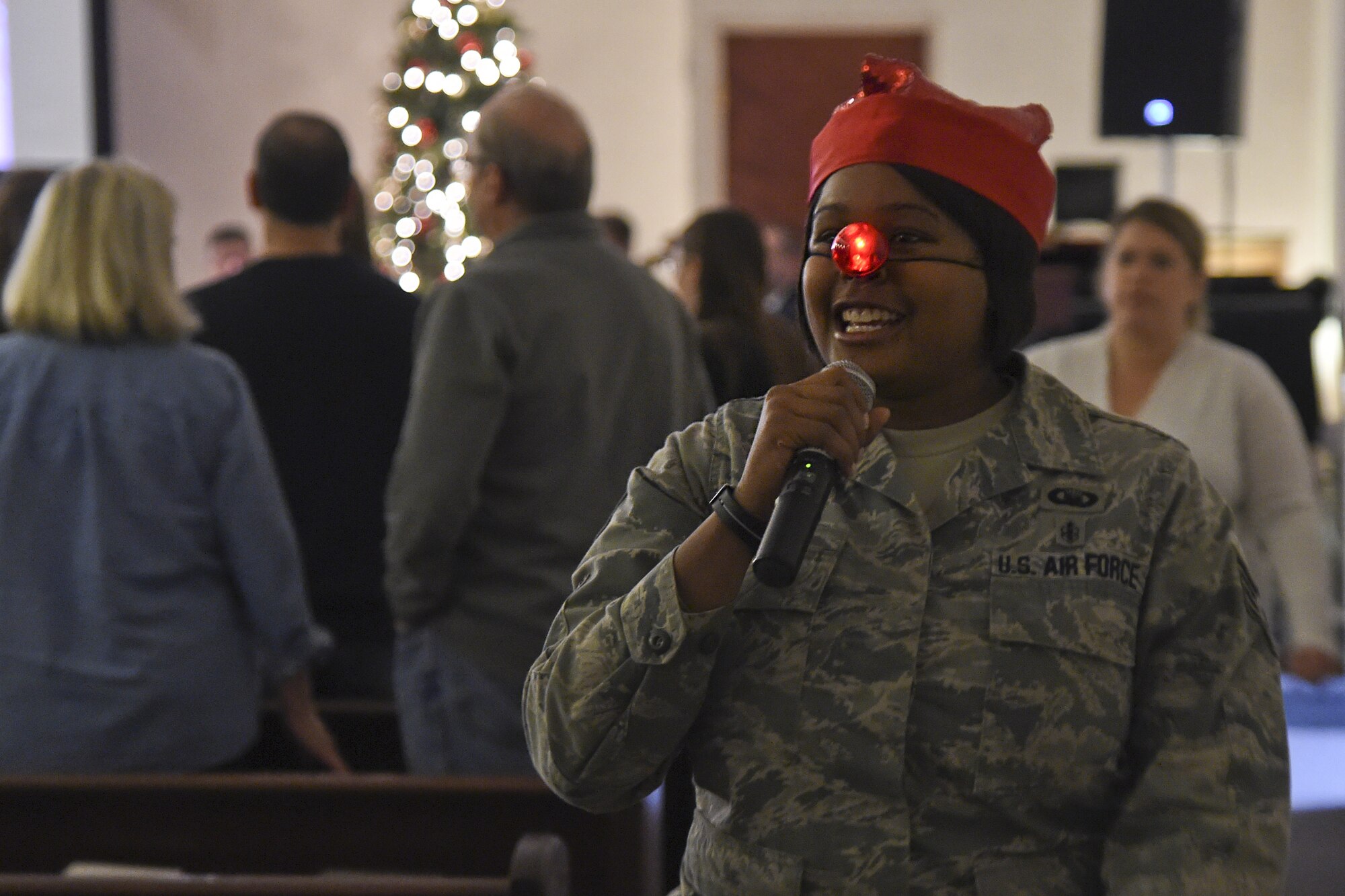 Staff Sgt. Keesha Brown, 11th Wing chaplain assistant, sings "Rudolph the Red-Nosed Reindeer" with the audience attending the Christmas Tree and Hanukkah Menorah Lighting on Joint Base Andrews, Dec. 3, 2014. The event featured storytelling, a performance by the United States Air Force String Band, the tree and menorah lighting and was capped off by a special guest appearance. (U.S. Air Force photo/ J.D. Maidens)