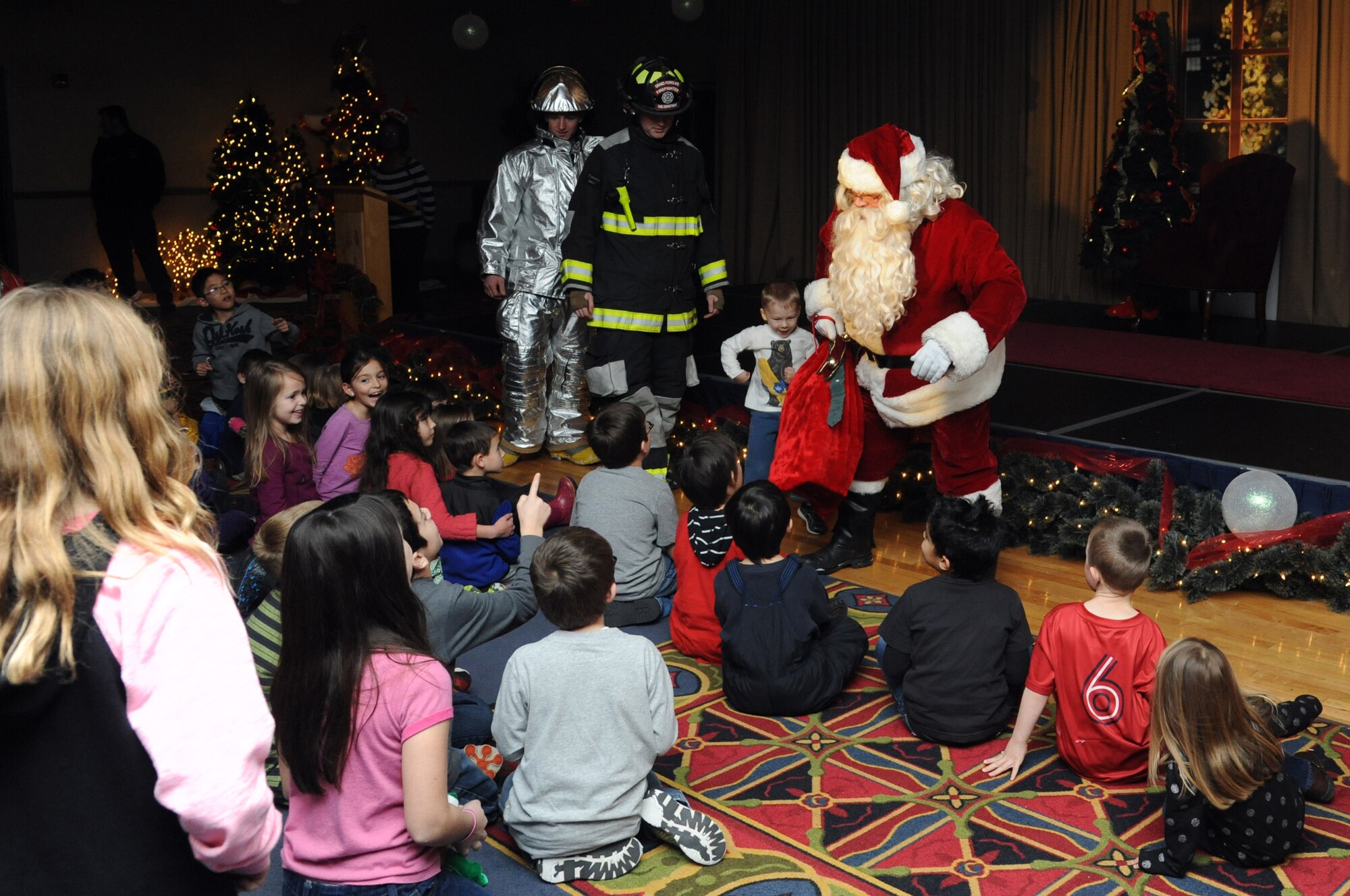 Santa Claus greets children at the Northern Lights Club on Grand Forks Air Force Base, N.D., Dec. 3, 2014. Santa was escorted to the club by members of the Grand Forks AFB Fire Department and stayed to have pictures taken with the children. (U.S. Air Force photo/Staff Sgt. David Dobrydney)