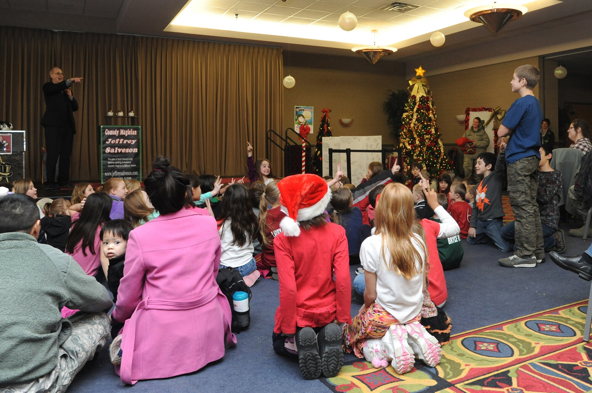 Magician Jeffrey Salveson interacts with the audience during his performance at the Holiday Tree Lighting ceremony at the Northern Lights Club on Grand Forks Air Force Base, N.D., Dec. 3, 2014. In addition to Salveson's magic show, the event featured carols and a visit from Santa Claus. (U.S. Air Force photo/Staff Sgt. David Dobrydney)