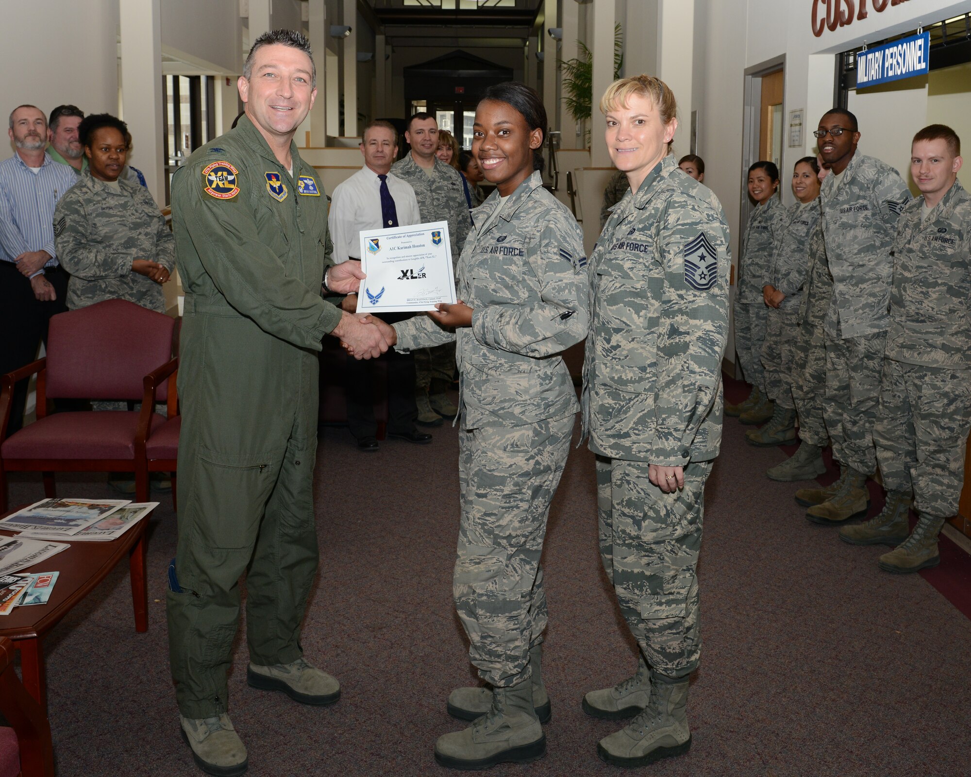 Airman 1st Class Karimah Houston, center, 47th Force Support Squadron Force Management apprentice, poses with Col. Brian Hastings, left, 47th Flying Training Wing commander, and Chief Master Sgt. Teresa Clapper, right, 47th FTW command chief, after being presented the XLer of the week award here Dec. 3, 2014. The XLer is a weekly award chosen by wing leadership and is presented to those who consistently make outstanding contributions to their unit and Laughlin. (U.S. Air Force photo by Airman 1st Class Jimmie D. Pike)(Released)