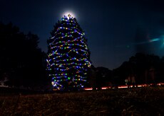 The Joint Base Charleston – Air Base  Christmas  tree shines brightly in front of the December moon  Dec. 3, 2014, at JB Charleston, S.C. Airmen, Sailors, civilians, families and friends gathered around the tree to sing carols, enjoy cookies, drink hot chocolate and to meet Santa Claus. (U.S. Air Force photo/Senior Airman Jared Trimarchi)