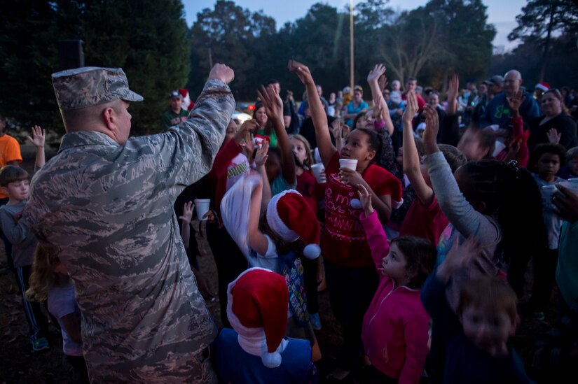 Colonel Jeffrey DeVore, Joint Base Charleston commander, asks for a volunteer to help light the Joint Base Charleston – Air Base Christmas tree Dec. 3, 2014, at JB Charleston, S.C. Airmen, Sailors, civilians, families and friends gathered around the tree to sing carols, enjoy cookies, drink hot chocolate and to meet Santa Claus. (U.S. Air Force photo/Senior Airman Jared Trimarchi) 