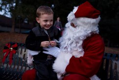 A happy young man tells Santa his wish list during the Christmas tree lighting ceremony Dec. 3, 2014, at Joint Base Charleston – Air Base, S.C. Airmen, Sailors, civilians, families and friends gathered to, sing carols, enjoy cookies and drink hot chocolate. (U.S. Air Force photo/Senior Airman Jared Trimarchi)