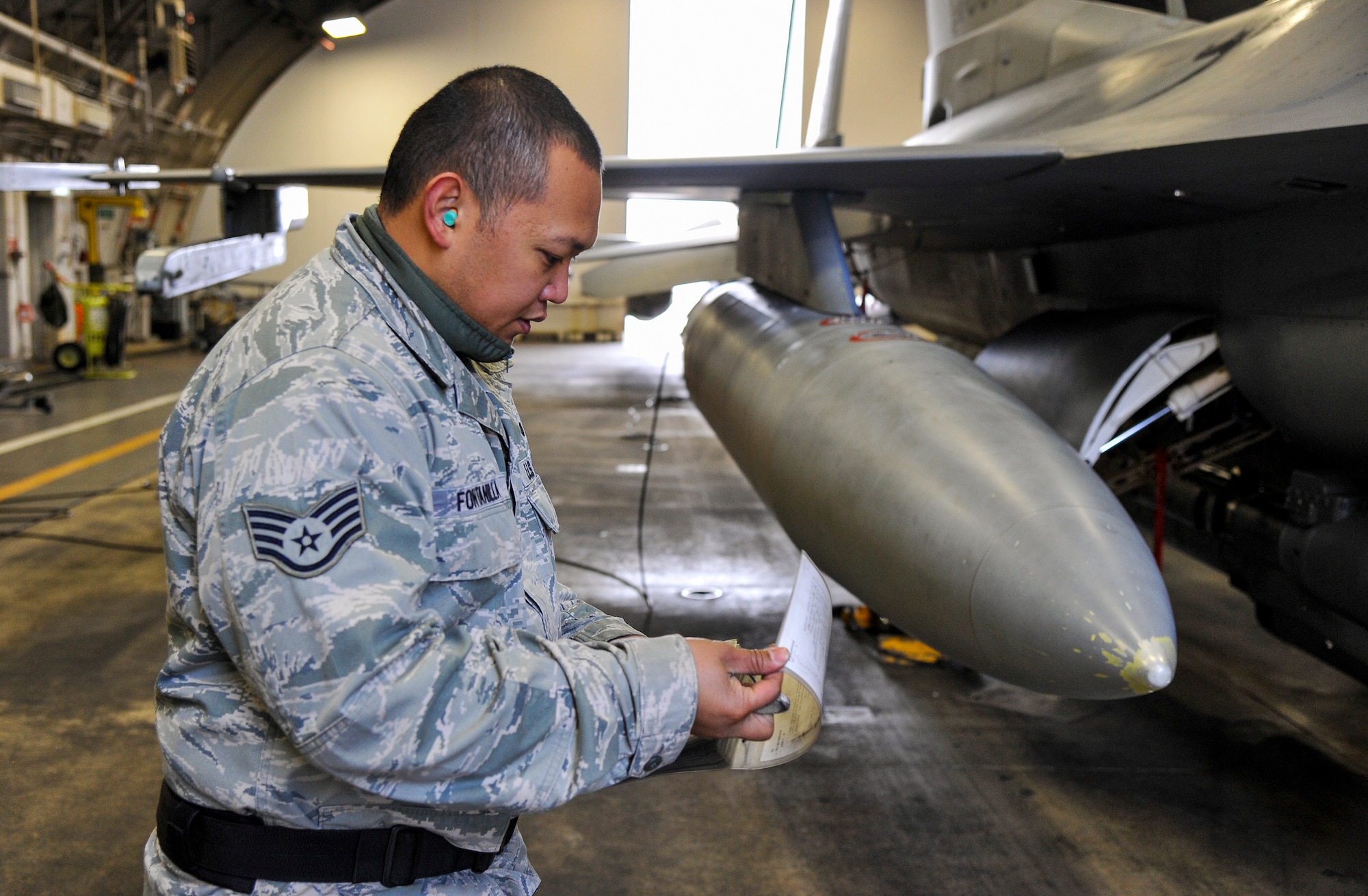 U.S. Air Force Staff Sgt. Eric Fontanilla, 13th Aircraft Maintenance Unit weapons load crew chief, consults a technical order checklist at Misawa Air Base, Japan, Dec. 4, 2014. Fontanilla and his weapons load crew team worked together to arm an F-16 Fighting Falcon in support of exercise Beverly Sunrise 15-1. During this exercise, several F-16s and approximately 200 Misawa Airmen will deploy to support exercise operations, making this exercise the first of its kind. (U.S. Air Force photo by Airman 1st Class Patrick S. Ciccarone/Released)