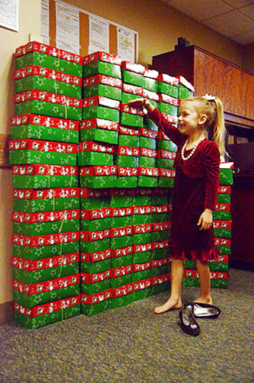 Lilly Bradley, 6, shows her mother where the top of her head reaches on a tower of Operation Christmas Child boxes stacked at the Liberty Chapel on Fort Campbell, Ky., Nov. 21, 2014. Lilly donated 100 boxes filled with school supplies and other gifts to ensure 100 less-fortunate children around the world have a present to open on Christmas morning. Lilly is the daughter of Erin and Army Spc. Adam Bradley, 96th Aviation Support Battalion, 101st Combat Aviation Brigade, 101st Airborne Division. U.S. Army photo by Michele Vowell