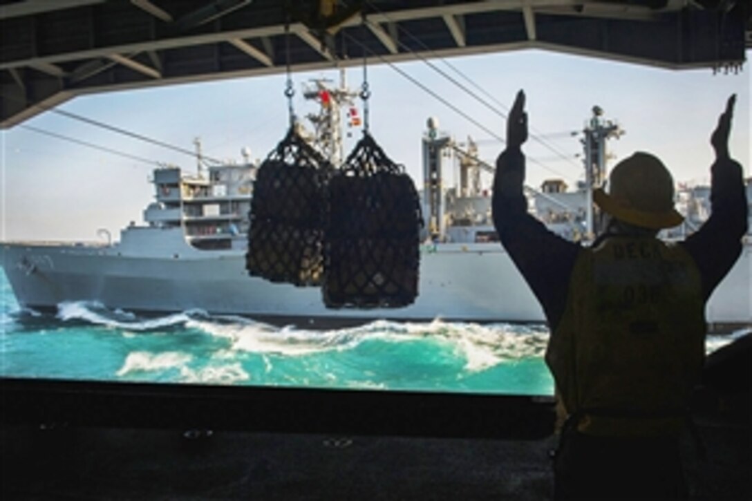 U.S. Navy Petty Officer 2nd Class Kevin Cotton directs cargo into the hangar bay of the aircraft carrier USS Carl Vinson during a replenishment-at-sea operation with ship USNS Rainier in the Arabian Gulf,  Dec. 3, 2014.