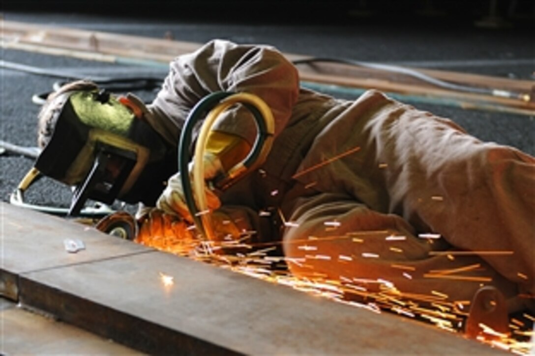 Jared Kennedy welds tracks used to transport a material holding tank in the hangar bay of the aircraft carrier USS Ronald Reagan in San Diego, Dec. 1, 2014. Kennedy is part of the Puget Sound Naval Shipyard team conducting maintenance on the ship. The Ronald Reagan is undergoing a planned incremental availability maintenance period at Naval Base Coronado, Calif. 