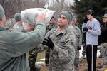 Senior Airman Travis Besette, of the 119th Civil Engineer Squadron, center, catches a sandbag to pass along a human chain of National Guard members March 16, Fargo, N.D. The North Dakota Airmen from the 119th Wing were woven in between local high school student volunteers in sandbag lines that extended from pallets on the street and in driveways, through garages and out back doors. The quickly rising river behind them reminded them of the urgency of their mission.