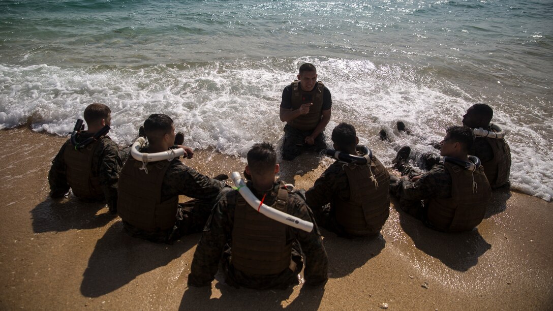 Staff Sgt. Rafael Garcialopez, center, passes Marine Corps Martial Arts Program fundamentals and knowledge to his squad Nov. 21, at Kin Blue, Okinawa, during the culminating event for Marine Corps Martial Arts Instructor course class 1-15. MCMAP focuses on real-life hand-to-hand combat survival techniques that also include leadership tie-ins that help build confidence and leadership in the Marines. The course was run by Headquarters and Support Battalion, Marine Corps Installation Pacific-Marine Corps Base Camp Butler, Japan. Garcialopez is martial arts instructor-trainer and chief instructor for the course. (Marine Corps Photo by Cpl. Joey S. Holeman, Jr./ Released)