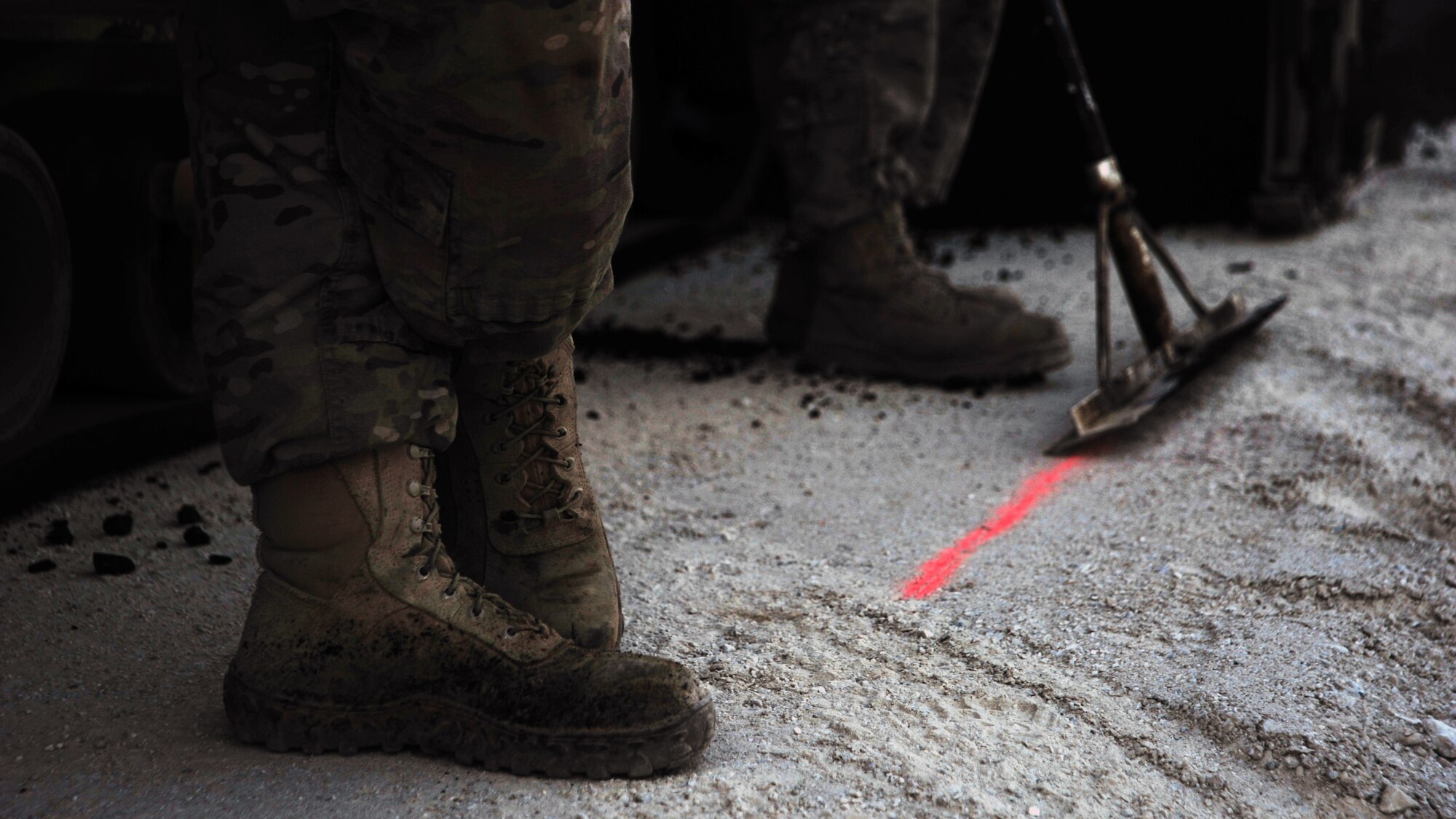 U.S. Air Force Airmen assigned to the 557th Expeditionary Rapid Engineer Deployable Heavy Operational Repair Squadron Engineers (RED HORSE) Squadron wait for a load of asphalt to arrive during a road completion project Dec. 2, 2014. When expelled from the paver, asphalt reaches temperatures greater than 300 degrees Fahrenheit. (U.S. Air Force photo by Staff Sgt. Whitney Amstutz/released)