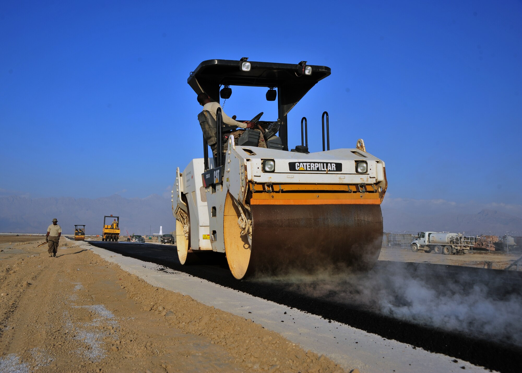 Steam rises from the blacktop as U.S. Air Force Staff Sgt. Antoine Davis, 557th Expeditionary Rapid Engineer Deployable Heavy Operational Repair Squadron Engineers (RED HORSE) Squadron pavement and construction, drives a roller over freshly-laid asphalt during a construction project Dec. 2, 2014 at Bagram Airfield, Afghanistan. The RED HORSE team, which travels throughout the Area of Responsibility completing high-value construction projects, laid out miles of asphalt during their time at the 455th Air Expeditionary Wing. (U.S. Air Force photo by Staff Sgt. Whitney Amstutz/released)