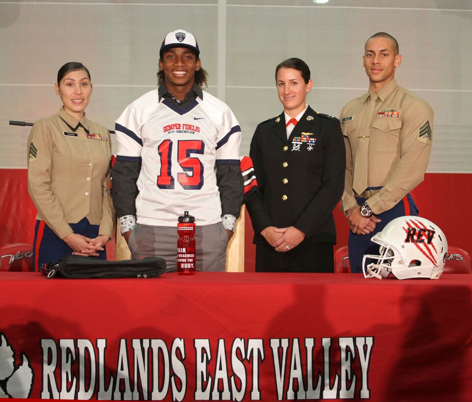 REDLANDS, Calif. - From left to right Sgt. Jasmine Duran, canvassing 
recruiter, Malik Lovette, recipient, Capt. Catherine Zeigler, Marine Corps 
Recruiting Station San Diego executive officer and Sgt. Kristopher Rouse, 
canvassing recruiter, pose for pictures during a 2015 Semper Fidelis 
All-American Bowl jersey presentation at Redlands East Valley High School in 
Redlands, Calif., Dec. 4. Lovette will be playing running back and wide 
receiver during the game taking place in Carson, Calif., Jan. 4, 2015. (U.S. 
Marine Corps photo by Sgt. Erica Kirsop/ RELEASED)
