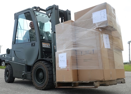 In this photo, an Operation Christmas Drop volunteer uses a forklift to transport boxes containing toys. Operation Christmas Drop is an annual humanitarian airlift mission that began in 1952 and supplies more than 50 islands with boxes that contain donations such as non-perishable food items, clothing, medical supplies, tools, toys and other various items. 